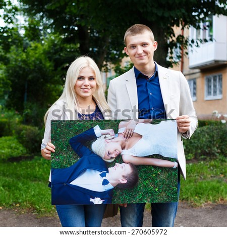 Bride and groom holding print after wedding day