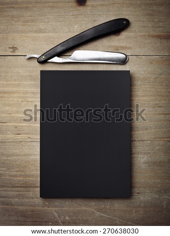 Straight razor and black paper on wood desk