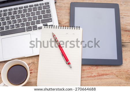 Laptop, smartphone, tablet and coffee cup with financial documents on wooden table