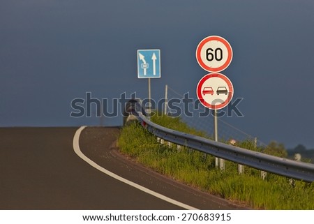 Traffic signs on the side of a road with stormy sky background