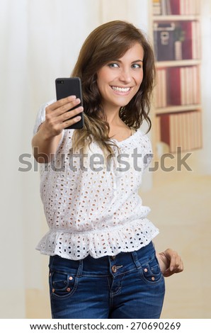 young casual beautiful hispanic woman using her cell phone taking a selfie