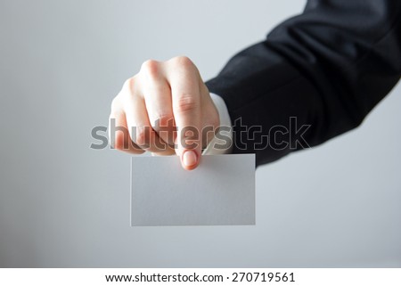 Businessman's hand holding blank business card  pass ticket on a grey background. Copy space for text.