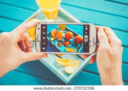 Woman taking picture of vintage tray with fruits on her smartphone. Top view