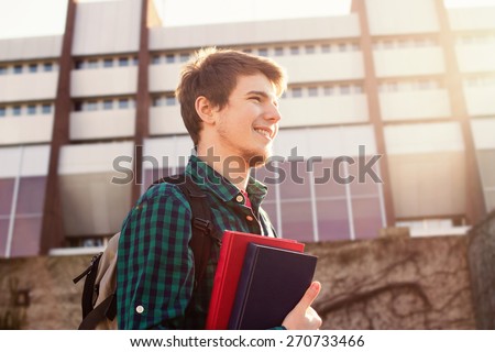 University.Smiling young student man holding a book and a bag on a university background .Young smiling student  outdoors Life style.City.Student. Royalty-Free Stock Photo #270733466