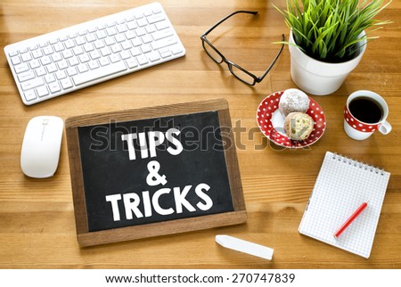 Handwritten tips & tricks on blackboard. Handwritten tips & tricks with chalk on blackboard, keyboard,notebook,glasses,cup of coffee,baking and green plant on wooden background