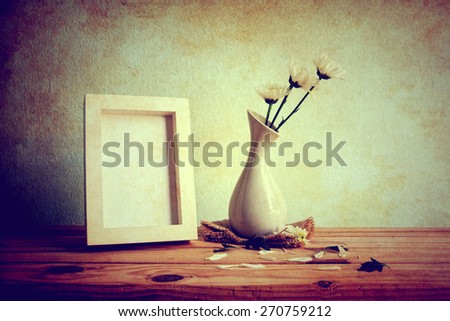 Vintage photo frame and flowers on wooden table over grunge background, Still life style 