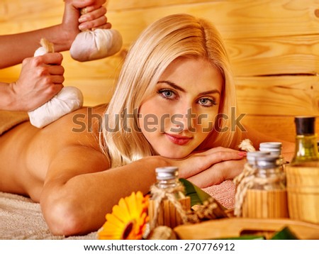 Blond woman getting herbal ball massage in spa. Look at camera.