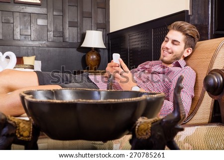 A handsome young man taking a selfie in a asian style hotel room.