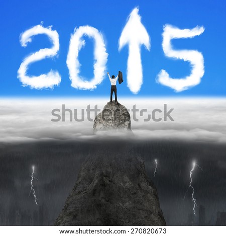 Businessman cheering on mountain peak for 2015 year arrow up sign shape clouds in the sky with opposite weather conditions background, blue sky cloudscape, dark overcast lightning raining cityscape