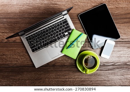 Office desk with laptop computer, tablet pc, planner, pen, mobile smartphone and cup of tea. 