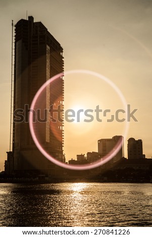 Panorama of Ho Chi Minh viewed over Saigon river. Breathtaking dramatic light of sunset is highlighted by lens flare effect created by vintage photo equipment.