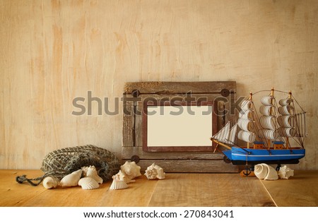 old nautical wooden frame, boat and natural seashells on wooden table