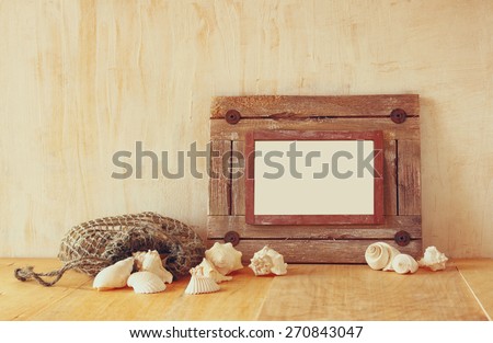 old nautical wooden frame and natural seashells on wooden table