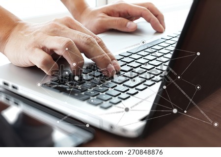 Close up of business man hand working on laptop computer with social network diagram on wooden desk as concept
