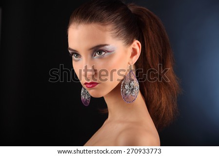 Beautiful girl with creative colorful makeup on a dark background studio
