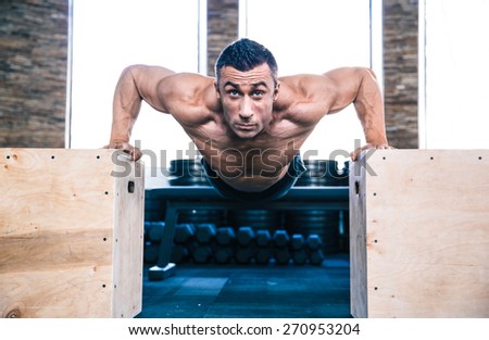 Handsome muscular man doing push ups on fit box at gym