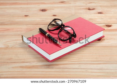 red book with glasses and pen on the wooden 