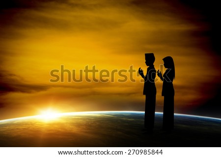 Silhouette muslim boy and girl praying at sunset. Elements of this image furnished by NASA