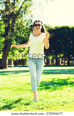 summer, leasure, vacation and people concept - smiling young woman wearing sunglasses standing in park