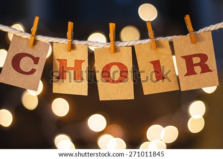 The word CHOIR printed on clothespin clipped cards in front of defocused glowing lights.