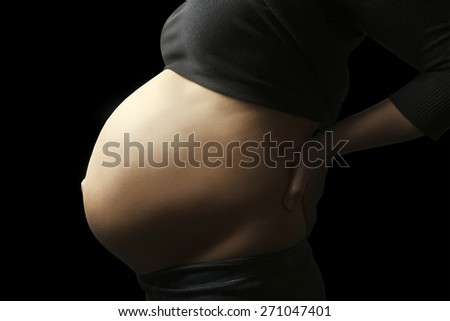Belly of pregnant woman on brown background