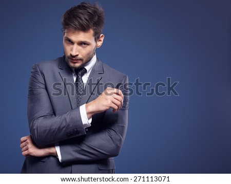 Handsome young business man standing on blue background