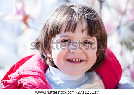 Small, expressive baby girl with natural light and spring background with magnolia flowers