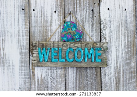 Teal blue welcome sign with country fabric heart hanging on white painted rustic wood fence