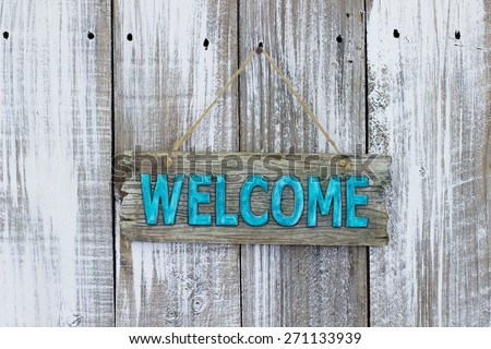 Teal blue welcome sign hanging on white painted weathered wood background