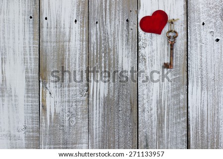 Brass skeleton key and red wood heart hanging on rustic whitewash painted wooden door; Valentines Day, Mothers Day and love concept background with white copy space
