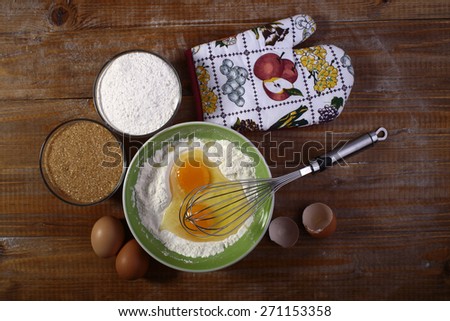 Set of ingredients and appliances for baking with yolk in flour on wooden table top, horizontal picture
