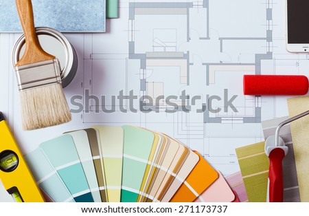 Painter and decorator work table with house project, color swatches, painting roller, brush and tools, top view