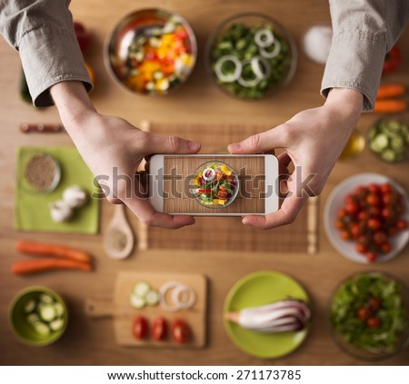 Man holding a smart phone hands close up, kitchen table worktop on background with fresh vegetables and utensils Royalty-Free Stock Photo #271173785