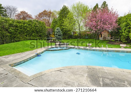 Backyard with outdoor inground residential private swimming pool and stone patio Royalty-Free Stock Photo #271210664