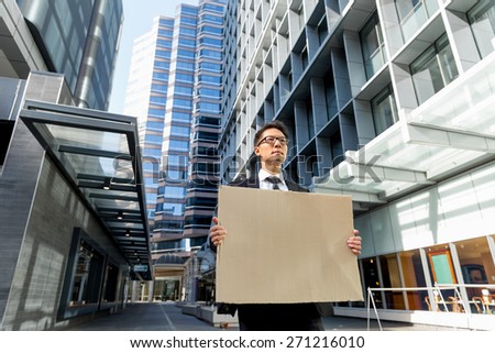 Businessman in a city street holding a blank banner