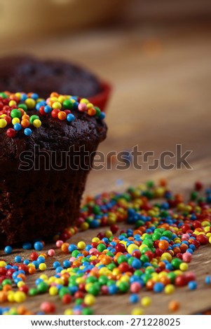 Chocolate cup cake and sweet colored glaze yellow red blue orange pink green color closeup, vertical picture