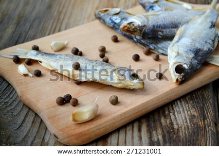 Salty stockfish cod on wooden board with gaarlic and pepper