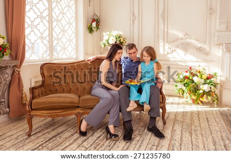 Father and mather reading book to her daughter in luxury living room