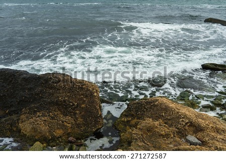 Large stones on a rocky coast washed by the waves