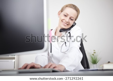 Close up Happy Woman Doctor Calling on the Telephone While Using her Computer on the Table