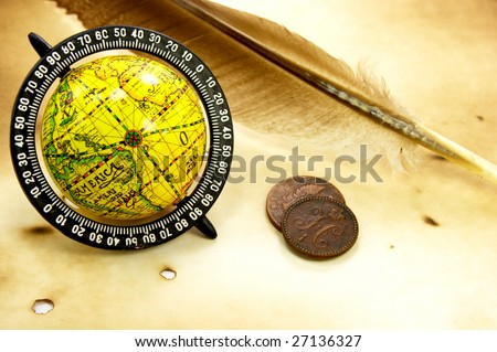 Antique globe, feather and old coins on grunge background