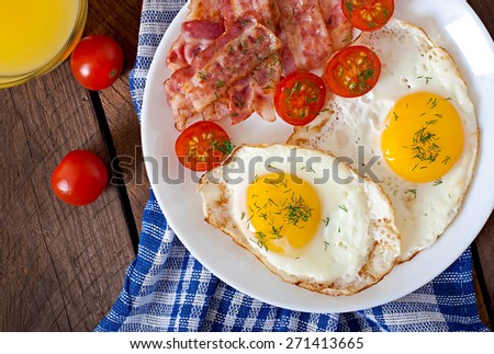 English breakfast - toast, egg, bacon and vegetables in a rustic style on wooden background. Top view.