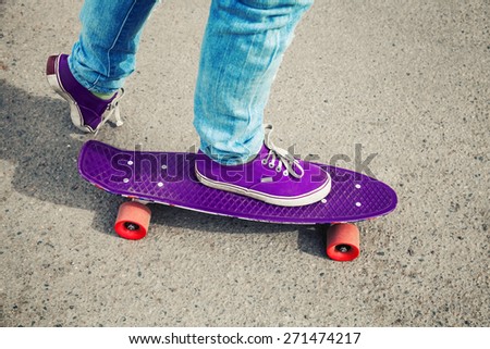 Skateboarder in jeans, feet fragment with skate, photo with retro tonal correction, instagram old style