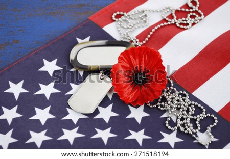 USA Memorial Day concept with dog tags and red remembrance poppy on American stars and stripes flag on dark blue vintage wood table. 