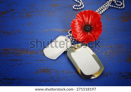 USA Memorial Day concept of red remembrance poppy on dark blue vintage distressed wood table, with soldiers dog tags, and vignette. 