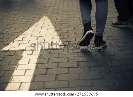 White arrow straight sign on street with walking people  