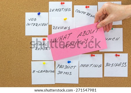 White paper notes with various written to-do tasks affixed to the corkboard.  Female hand holding a red card with the inscription "What about family" in the foreground.