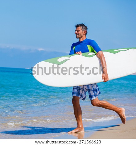 Strong young surf man runing at the beach with a surfboard.