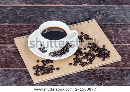 A cup of cafe latte and book on wooden table