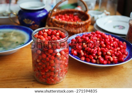 Fresh ripe wild strawberries in a jar on a wooden table